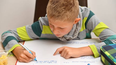 Das Bild zeigt einen Jungen beim Lernen und Hausaufgaben machen.