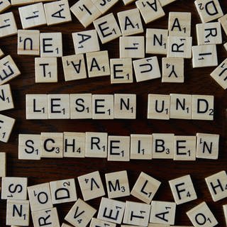 Das Bild zeigt die Wörter "Lesen" und "Schreiben" gelegt aus kleinen Holzbuchstaben.