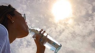 Eine Frau trinkt Wasser an einem sonnigen Tag.
