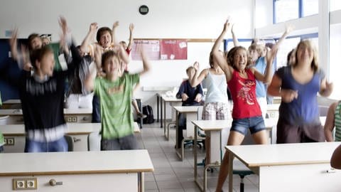 Kinder springen von ihren Stühlen im Klassenzimmer auf.