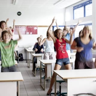 Kinder springen von ihren Stühlen im Klassenzimmer auf.
