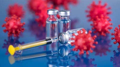 Das Bild zeigt eine Impfkanüle vor dem Hintergrund verschiedener roter Viren-Modelle.