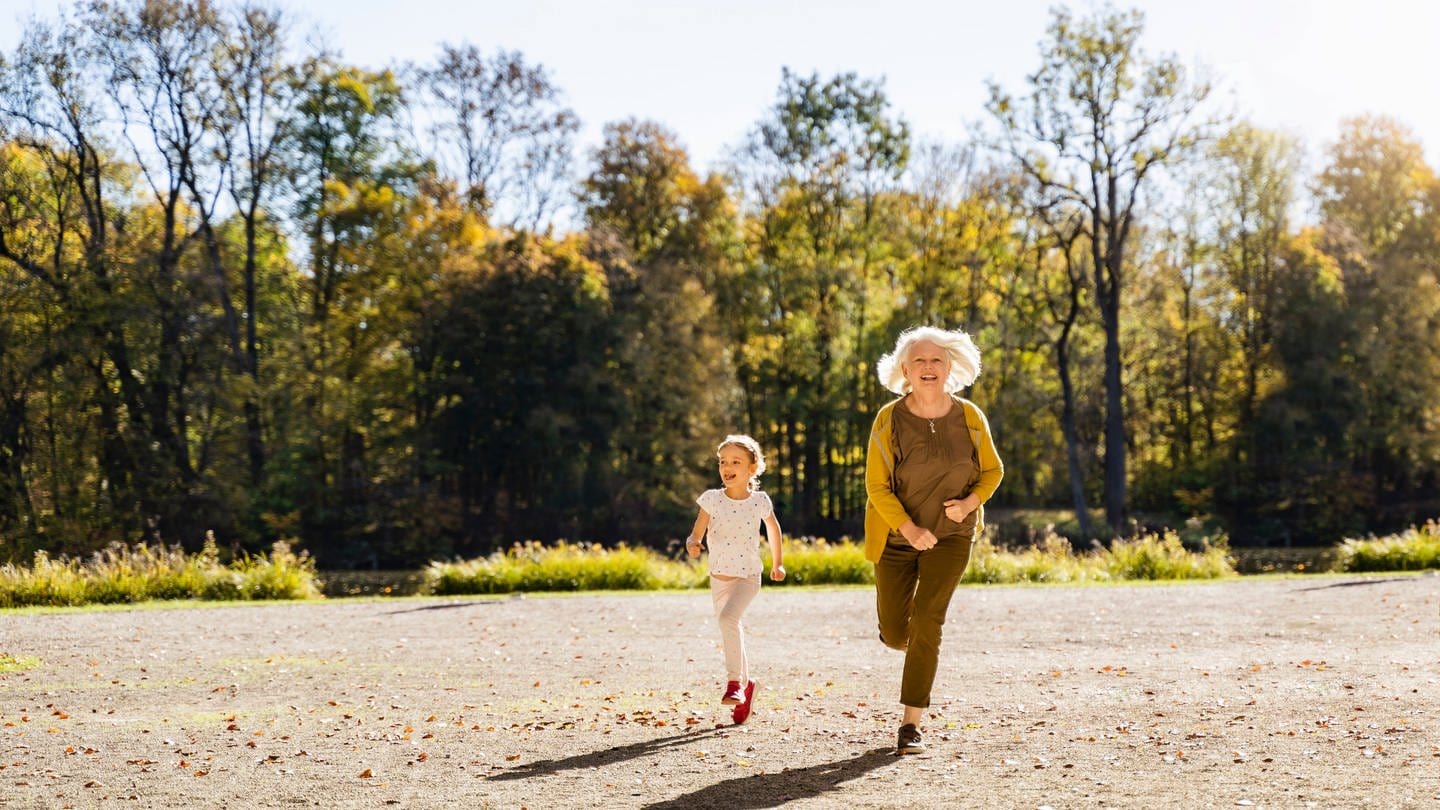 Das Bild zeigt eine ältere Frau und ein kleines Mädchen, die nebeneinander laufen.