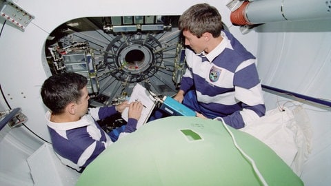 Dezember 1998: Missionskommandant Robert D. Cabana (links) und der russische Kosmonaut Sergei K. Krikalev (rechts) besprechen Ihre jeweiligen Aufgaben für das in den USA gebaute Unity-Modul der Internationalen Raumstation ISS. 