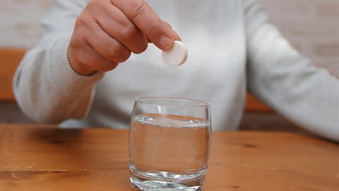 Ein Mann hält eine Brausetablette über ein Glas Wasser, tags: Natrium, Bluzhochdruck, Ärzte warnen