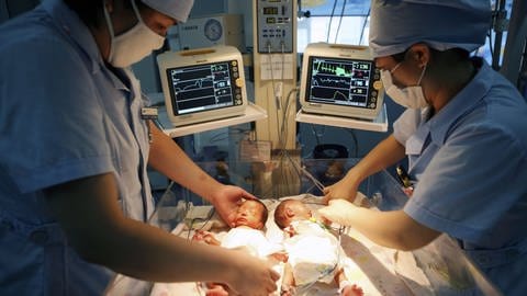 Ärzte versorgen frühgeborene Zwillinge auf einer Frühchen-Intensivstation. 