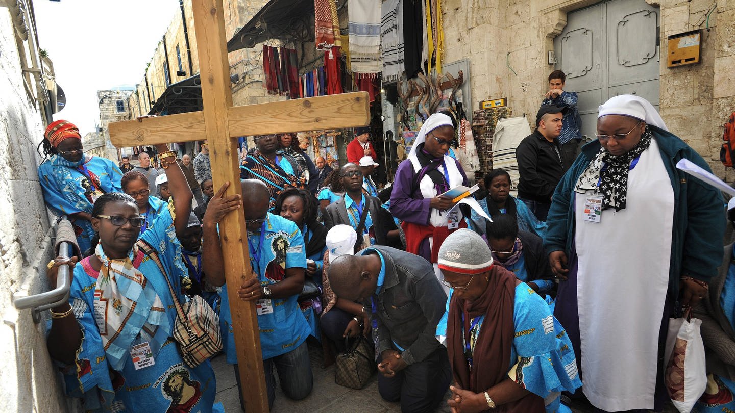 Pilgerinnen und Pilger aus Afrika tragen an Karfreitag auf der Via Dolorosa in der Altstadt von Jerusalem ein grosses Holzkreuz im Gedenken an den Leidensweg Jesu zur Kreuzigung