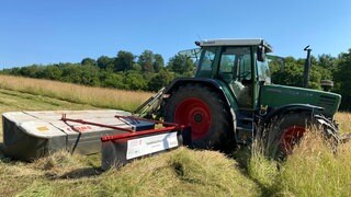 Traktor mit Mähwerk und Insektenscheuche