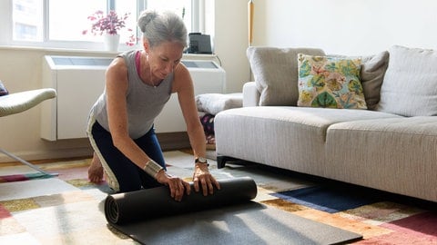 Ältere Dame mit einer Yogamatte