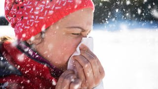 Eine Frau putzt sich die Nase im Schnee.