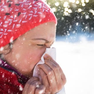 Eine Frau putzt sich die Nase im Schnee.
