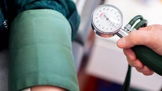 Ein Arzt misst den Blutdruck einer Patientin (Symbolbild).