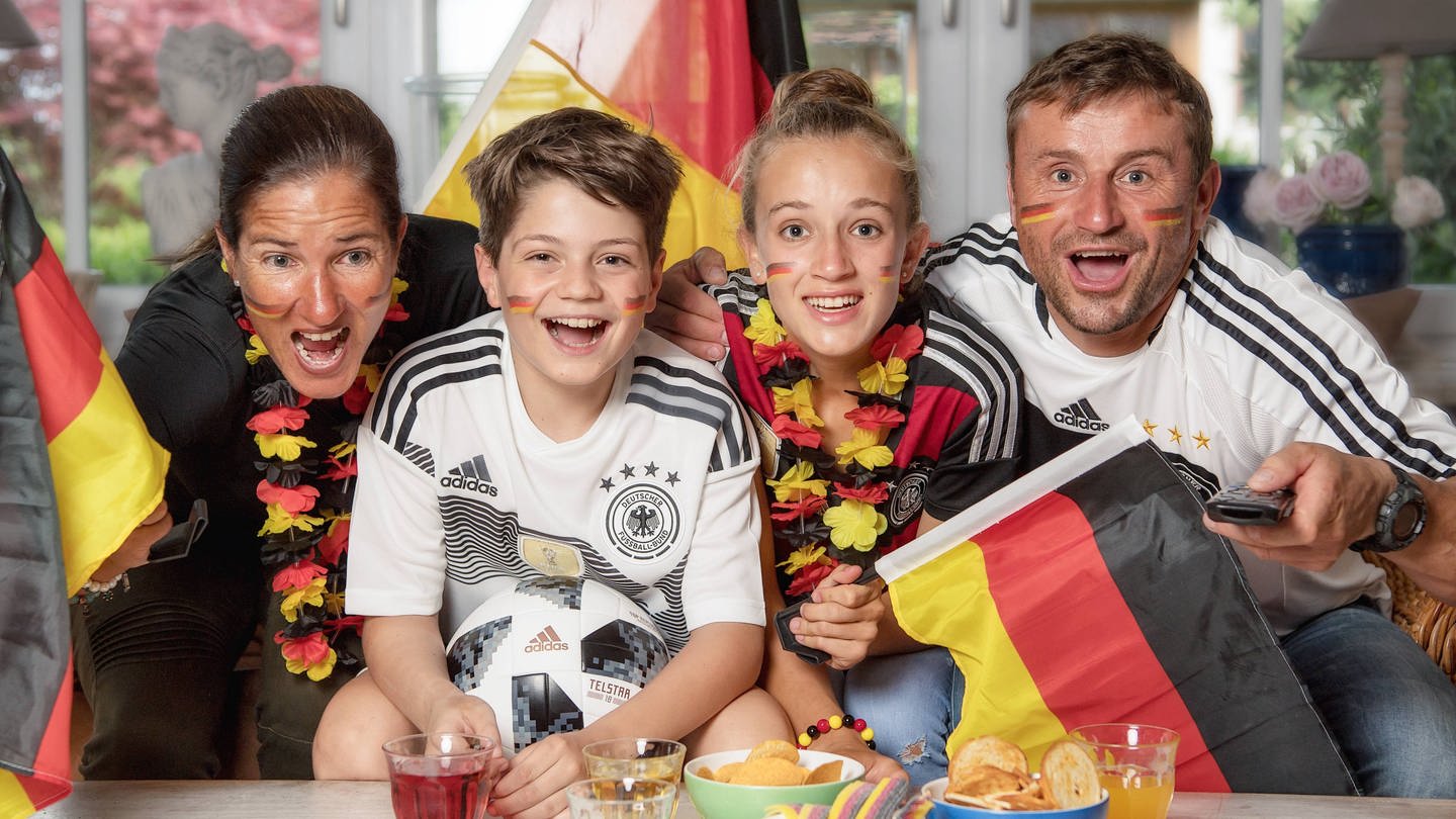 Es wird gejubelt, gesungen, geweint und geflucht: Deutschland ist im sprichwörtlichen Fußball-Fieber. Die Emotionen der Fans sind dabei stark von der sozialen Umgebung abhängig.  Familie schaut zusammen Fußball