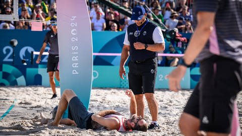 Volleyballer Clemens Wickler am Boden eines Beach-Volleybalfelds - er stürzte bei der Olympia 2024 über eine Netzkamera und zog sich eine Verletzung zu.