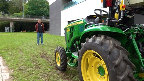 Ein kleiner, autonom fahrender Traktor fährt für einen Test auf einen Menschen zu.