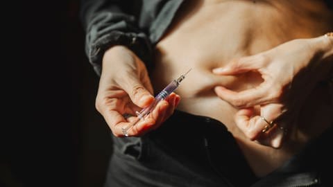 Mann mit Diabetes spritzt sich Insulin in den Bauch.