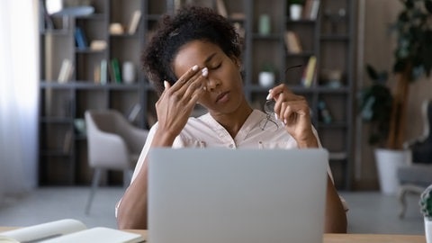 Frau vor Laptop reibt sich das Auge