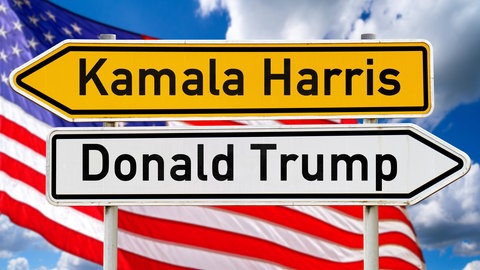 Symbolbild von zwei Schildern, die in entgegengesetzt Richtungen zeigen, auf einem steht "Kamala Harris", auf dem anderen "Donald Trump", dahinter weht die Flagge der USA, tags: Desinformation Rolle spielt USA Fake