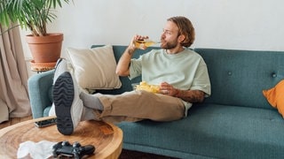 Ein Mann auf der Couch mit Bier und Chips, tags: Fakten Männergesundheit Männer Fakten Gesundheit