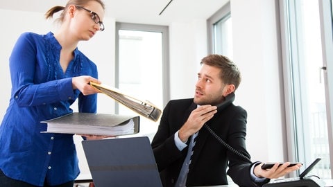  Ein junger Mann ist an seinem Arbeitsplatz überfordert und bekommt zusaetzliche Aufgaben. Die PIAAC-Studie zeigt, dass in Deutschland unter Erwachsenen diejenigen mit höheren Kompetenzen auch meist mehr verdienen.