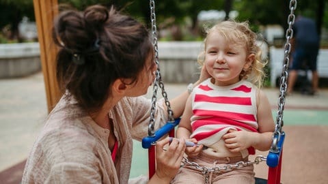 Eine Mutter gibt ihrer kleinen Tochter auf einer Schaukel eine Insulininjektion, tags: Diabetes Typ Kinder Covid Neuerkrankungen