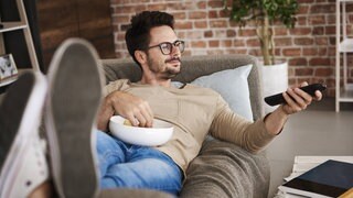 Person auf der Couch mit Chips